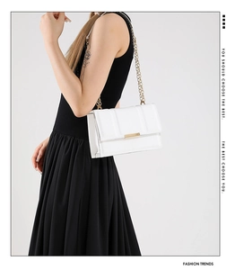 Detailed view of a white leather chain bag with elegant gold hardware and rectangular clasp