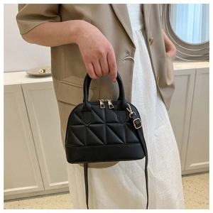 Detail of black quilted shell handbag with gold hardware and removable shoulder strap