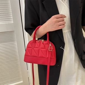 Detail of red shell handbag with triangular quilted pattern and gold zipper hardware