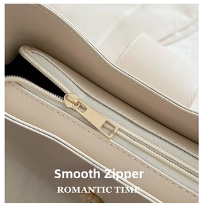 Close-up of smooth golden metal zipper and stitching on minimalist beige handbag