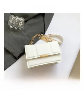 Close-up of white quilted leather crossbody bag with gold chain and metal buckle
