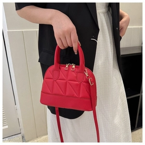 Close-up of red quilted shell handbag with gold zippers and adjustable shoulder strap
