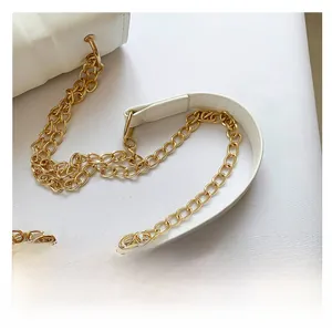 Detailed close-up of premium gold metal chain strap on a white quilted leather handbag