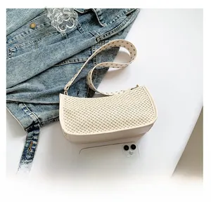 Detail of woven armpit bag with metal eyelet strap and smartphone for size reference