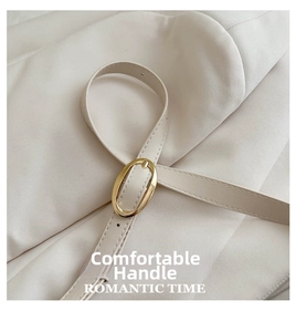 Detail of cream leather shoulder strap with elegant oval gold buckle and fine stitching