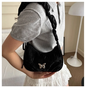 Detail of black satin crescent bag with scrunchie strap and silver butterfly buckle
