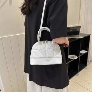 Detail of white quilted shell bag with golden zippers and detachable shoulder strap
