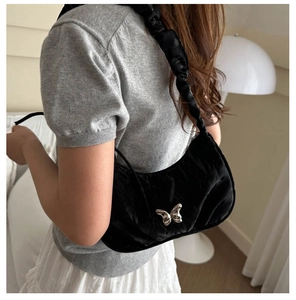 Close-up of black pleated underarm bag with silver butterfly charm and ruched strap