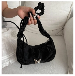 Detail of black crescent shoulder bag with pleated handle and silver butterfly buckle