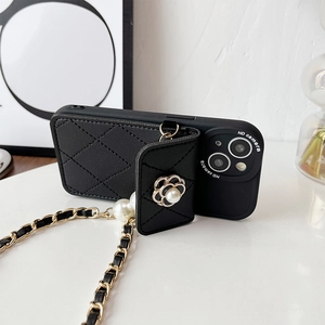 Detail of camellia flower and pearl charm on black quilted leather crossbody phone case
