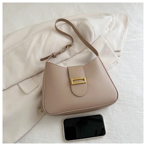 Detail of khaki leather shoulder bag with gold clasp shown with phone for scale
