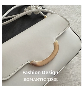 Detail of cream crossbody bag featuring a golden crescent buckle and litchi texture