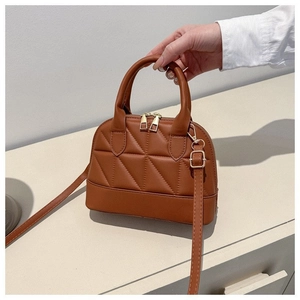 Detailed view of the quilted texture and golden zipper on the brown shell-shaped bag