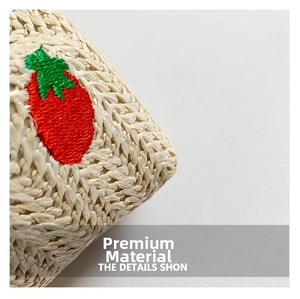 Macro shot of beige woven straw texture with fine red and green strawberry embroidery detail