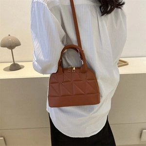Close-up of brown quilted shell bag with dual zippers and minimalist interior styling