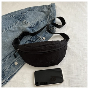 Close-up of black pleated texture chest bag with adjustable strap and buckle details