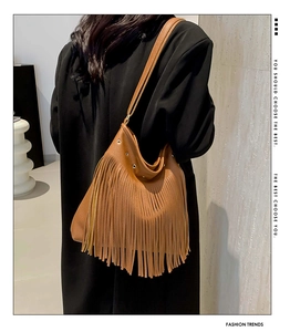 Detail of brown leather bohemian fringe shoulder bag with long tassels and studs