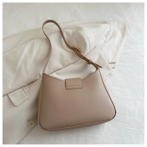 Detail view of khaki leather shoulder bag with adjustable strap on a light suit jacket