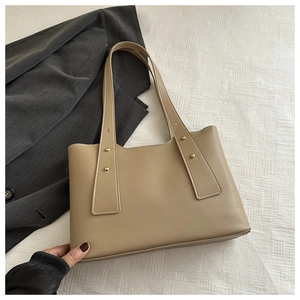 Detail of khaki faux leather tote bag with wide strap and gold metal stud accents