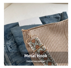 Detail of golden metal hook and geometric ethnic pattern strap on woven tote bag