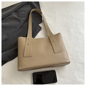 Detail view of khaki faux leather tote bag with elegant gold rivet accents on handles