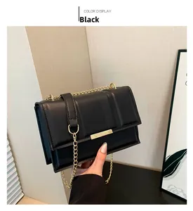Detail view of black square crossbody bag showing side thickness and golden chain strap