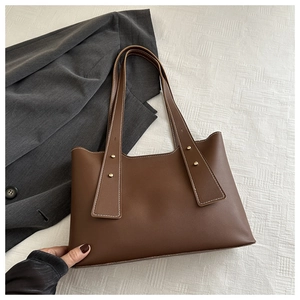 Close-up of brown tote bag with white contrast stitching and gold rivet hardware detail