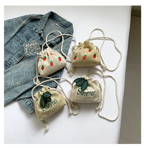 Detail of four woven straw bucket bags featuring strawberry and Summer embroidery designs