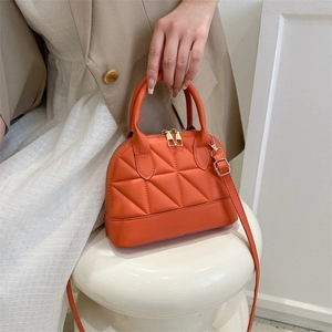 Detail of orange quilted shell handbag with gold zippers and detachable shoulder strap