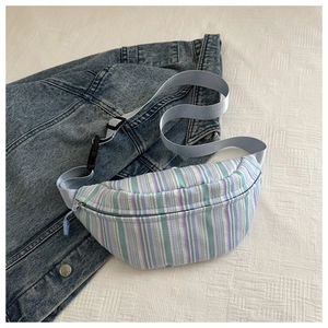 Détail du sac banane rayé avec bandoulière réglable sur fond de veste en jean