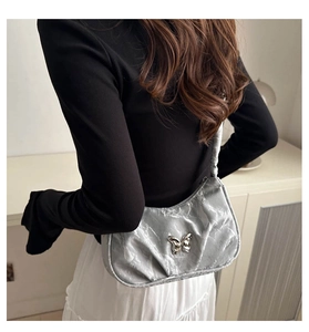 Detailed view of silver pleated hobo bag with metallic butterfly clasp on model