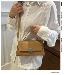 Detail of tan leather crossbody bag with crocodile texture and silver metal buckle
