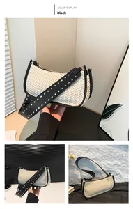 Detail of straw woven underarm bag with black PU strap and silver punk metal rivets