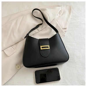 Detail of black half-moon bag with a textured gold metallic buckle on white fabric