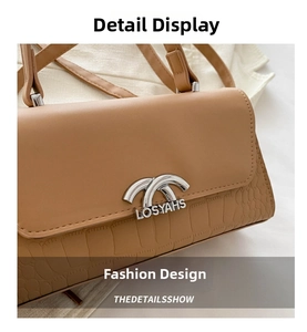 Detail of brown crossbody bag featuring crocodile embossed texture and silver metal buckle
