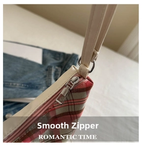 Detail view of smooth silver zipper and plaid fabric on a retro shoulder tote bag
