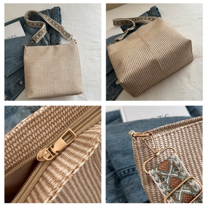 Detail of woven straw bucket bag showing wide bohemian strap and golden hardware accents