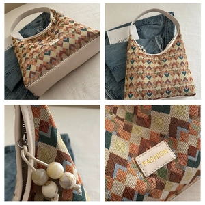 Detail view of woven shoulder bag featuring geometric patterns and marble bead zipper pull