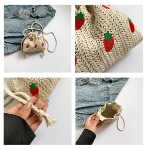 Detail view of woven straw bucket bag with red strawberry embroidery and cotton rope straps