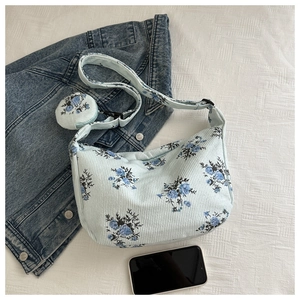 Detail view of light blue corduroy dumpling bag with vintage floral patterns and mini pouch