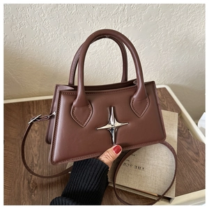 Détail du sac à main en cuir marron foncé avec étoile argentée et doubles poignées épaisses