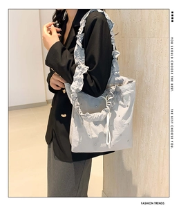 Detail of grey tote bag with ruffled handles and metallic stud accents in a lifestyle view