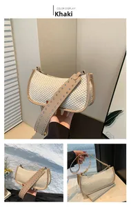 Detail of khaki leather trim and silver studs on a straw woven crossbody bag