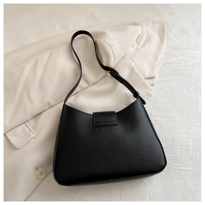 Detail of black faux leather underarm bag featuring magnetic flap and golden buckle strap
