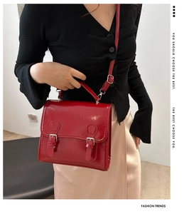 Detailed macro view of vibrant red patent leather texture and dual buckle on the bag