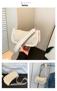 Detail of white straw woven underarm bag with silver stud accents on wide shoulder strap
