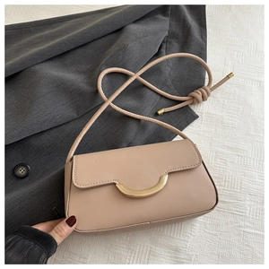 Détail d'un petit sac beige avec fermoir demi-lune doré et bandoulière en corde nouée