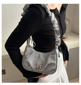 Detail of silver metallic ruched underarm bag with butterfly buckle and gathered strap