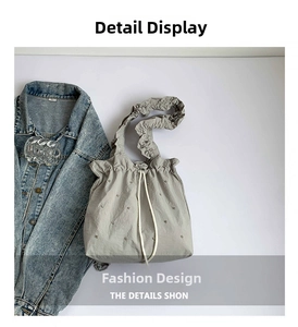 Detail of grey drawstring tote bag with ruffle strap and metallic rivet accents