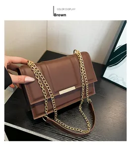 Close-up of brown faux leather shoulder bag with gold bar accent and metal chain strap